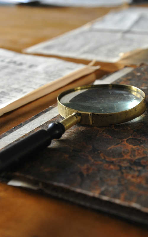 magnifying glass sitting on closed note book, open book beside it